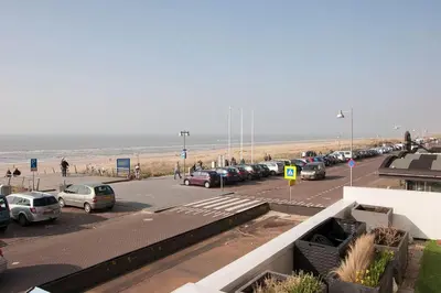 a parking lot with cars parked next to the beach at Zonnehoek 63 in Egmond aan Zee