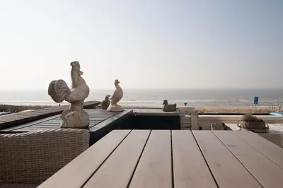 a table with chairs and a view of the ocean at Zonnehoek 63 in Egmond aan Zee