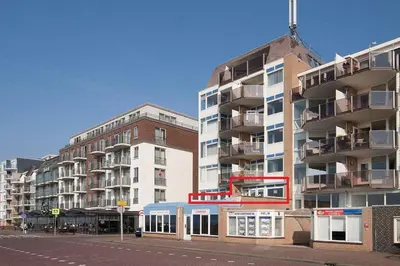 a tall apartment building with a bus in front of it at Zonnehoek 63 in Egmond aan Zee