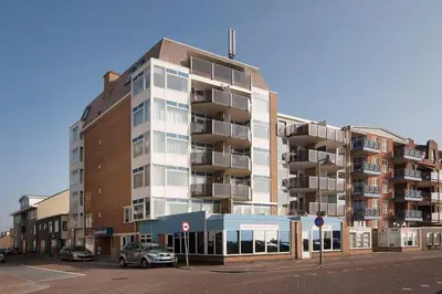 a tall building with a car parked in front of it at Zonnehoek 63 in Egmond aan Zee