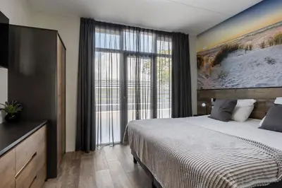 a bedroom with a large bed and a large window at Appartementen De Wilg - Adults only in Noordwijk aan Zee