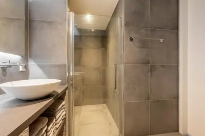 a bathroom with a shower with a white sink at Appartementen De Wilg - Adults only in Noordwijk aan Zee