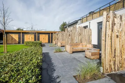 a row of wooden benches next to a fence at Appartementen De Wilg - Adults only in Noordwijk aan Zee