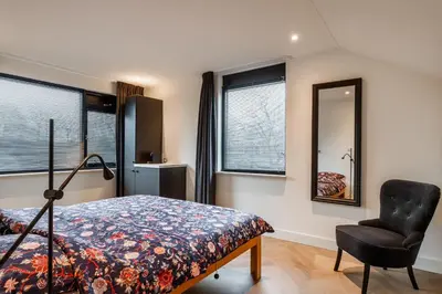 a bedroom with a bed and a chair and windows at Easy Sleep Lelystad in Lelystad