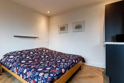 a bedroom with a bed with a floral blanket on it at Easy Sleep Lelystad in Lelystad
