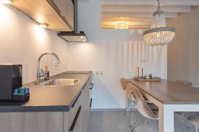 a kitchen with a sink and a counter with stools at Cosea Beach House in Zandvoort