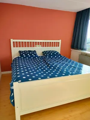 a white bed in a room with a red wall at Vroonenburch in Burgerbrug