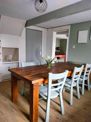 a dining room with a wooden table and white chairs at Vroonenburch in Burgerbrug