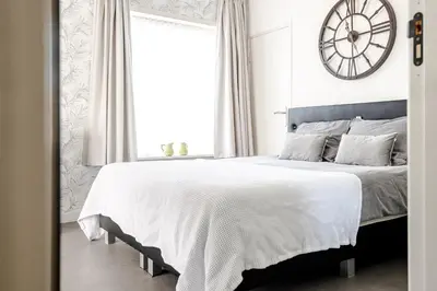 a bedroom with a large bed with a clock on the wall at Beach and Dunes Studio - Free Parking in Zandvoort