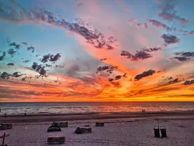 a sunset on a beach with chairs on the sand at Beach and Dunes Studio - Free Parking in Zandvoort