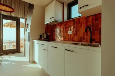 a kitchen with white cabinets and a view of the ocean at Venti Beach Houses in Zandvoort