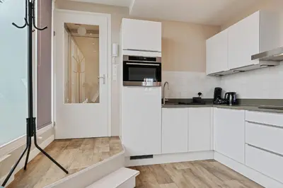 a kitchen with white cabinets and a refrigerator at Apartment at the harbor in Monnickendam