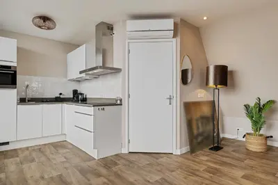 a kitchen with white cabinets and a sliding door at Apartment at the harbor in Monnickendam