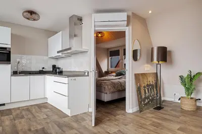 a kitchen with white cabinets and a bed in a room at Apartment at the harbor in Monnickendam