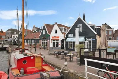 a boat is docked in a marina with houses at Apartment at the harbor in Monnickendam