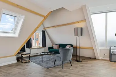 a living room with a green chair and a table at Apartment at the harbor in Monnickendam