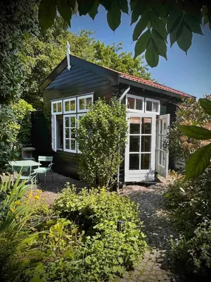 a small black cottage with a white door at t Ateliertje Noort in Bergen
