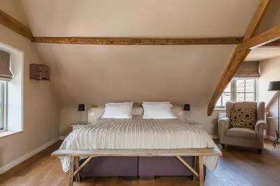 a bedroom with a large bed and a chair at Abbey Abcoude in Abcoude