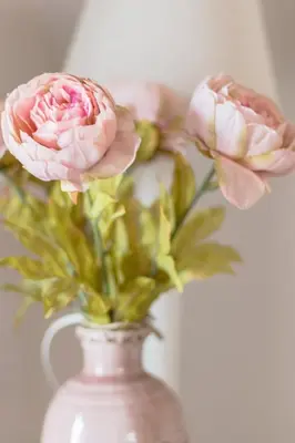 a white vase with pink flowers in it at Abbey Abcoude in Abcoude