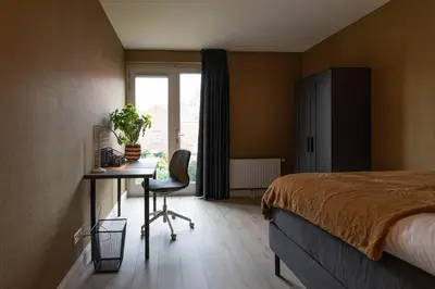 a bedroom with a bed and a desk and a window at Luxe 3-kamer Penthouse met dakterras in het centrum van Hoorn in Hoorn