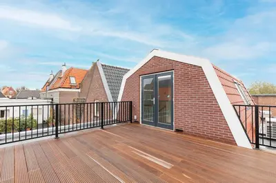 a large deck with a brick wall and a building at Luxe 3-kamer Penthouse met dakterras in het centrum van Hoorn in Hoorn