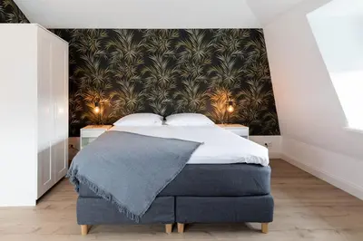 a bedroom with a bed with a black and gold wallpaper at Luxe 3-kamer Penthouse met dakterras in het centrum van Hoorn in Hoorn