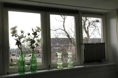 a window sill with four green glass bottles on it at Bed and breakfast Hoeve Spoorzicht in Papekop