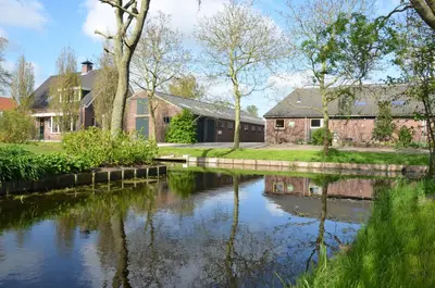 a house with a river in front of it at Bed and breakfast Hoeve Spoorzicht in Papekop