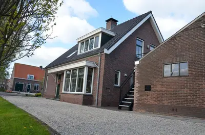 a brick house with a stairway to the front door at Bed and breakfast Hoeve Spoorzicht in Papekop