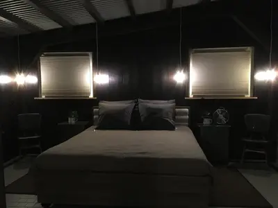 a bedroom with a large bed and two windows at Boerderij Honswijck in Weesp
