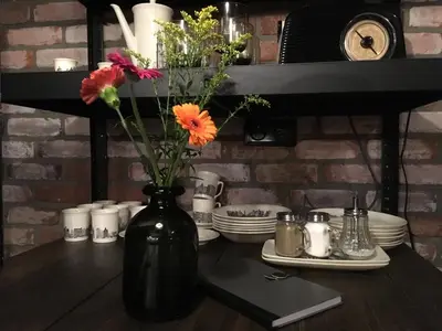 a black vase with flowers in it on a table at Boerderij Honswijck in Weesp