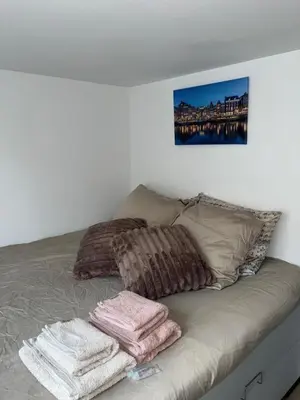 a bed with three pillows and towels on it at WaalPlaat's B&B in Amsterdam