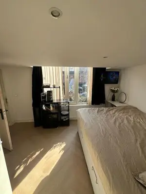 a bedroom with a bed and a large window at WaalPlaat's B&B in Amsterdam