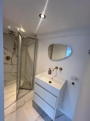a white bathroom with a sink and a shower at WaalPlaat's B&B in Amsterdam