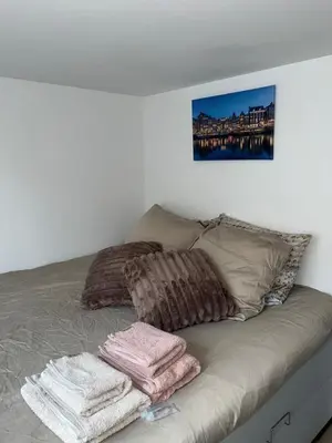 a bed with three pillows and towels on it at WaalPlaat's B&B in Amsterdam