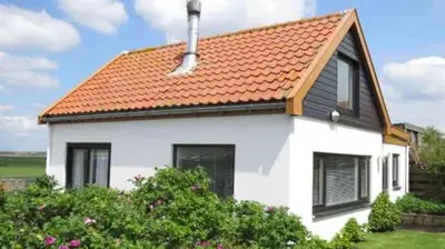 a white house with an orange roof at Vakantiehuis Camperduin in Schoorl