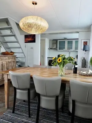 a dining room table with chairs and a vase of flowers at Vakantiehuis Camperduin in Schoorl