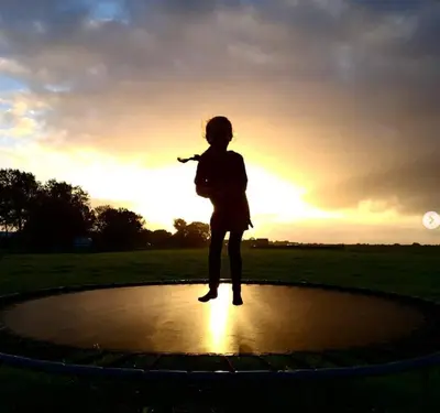 a girl is standing on a circle with the sunset in the background at Group accommodation Huize Blokland on nature farm - 14p in Hem