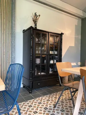 a black cabinet with dishes in it in a dining room at Group accommodation Huize Blokland on nature farm - 14p in Hem