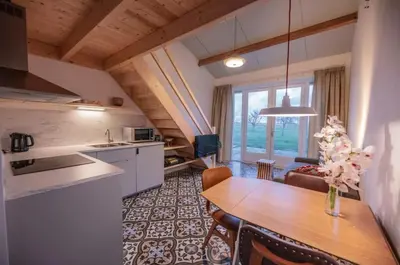 a kitchen and living room with a table and chairs at Group accommodation Huize Blokland on nature farm - 14p in Hem