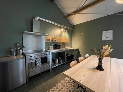 a kitchen with a table and a stove and a dining room at Group accommodation Huize Blokland on nature farm - 14p in Hem