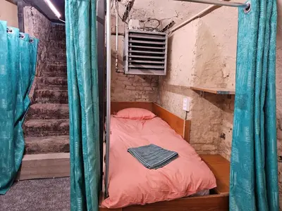 a small bed in a room with blue curtains at Overnachten aan de Werf in Utrecht