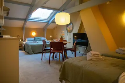 a bedroom with two beds and a table with chairs at Familielogement De Oude Beltoren in Utrecht