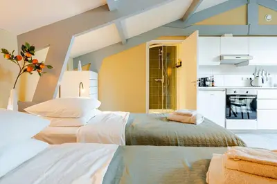two beds in a room with a kitchen at Familielogement De Oude Beltoren in Utrecht