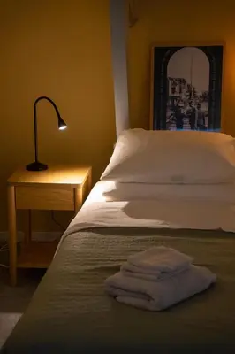 a bed with a lamp and a pile of towels on it at Familielogement De Oude Beltoren in Utrecht
