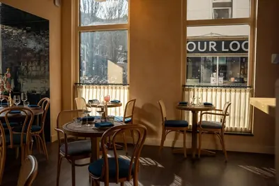 a restaurant with tables and chairs and a sign on the window at Léo Léo in Utrecht