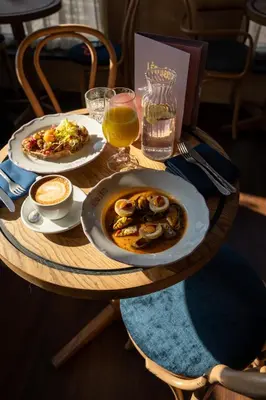 a wooden table with two plates of food and drinks at Léo Léo in Utrecht
