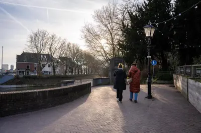 two people walking down a sidewalk next to a street light at Léo Léo in Utrecht