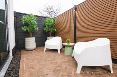 a patio with two white chairs and potted plants at Vakantie in Noordwijk in Noordwijk