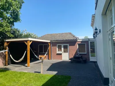 a patio with a hammock and a house at Villa free standing 25 min Amsterdam 10 min beach in Akersloot